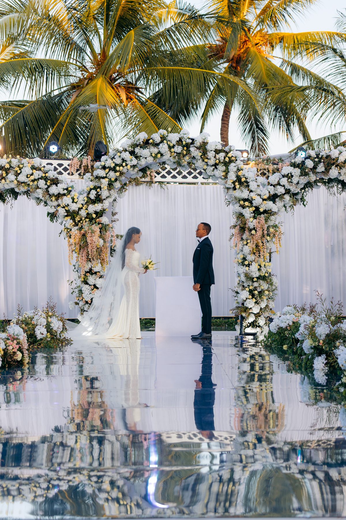 Ali & Dr. Lucy wedding in Tanga, Tanzania, by Kevins Events — the couple facing beneath the floral arch