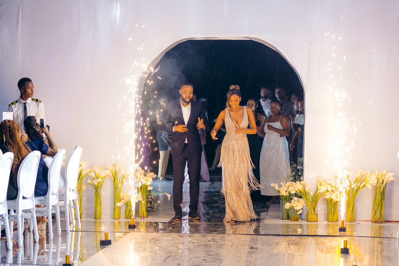 Couple grand entrance through white arch with cold sparklers — Kevins Events Tanzania